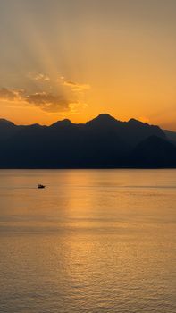 A tranquil sunset over a vast mountain range reflecting on calm waters.