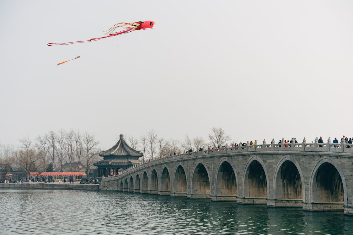 People On A Bridge Watching Kites Fly