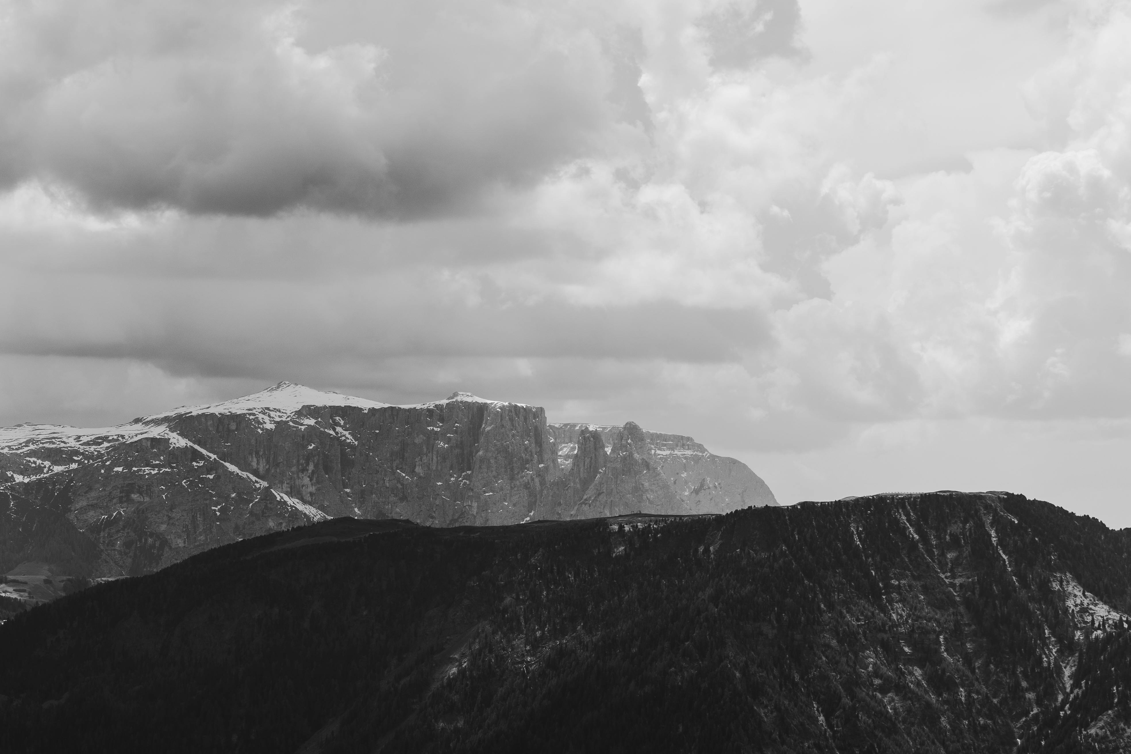Monochrome view of rugged mountains under dramatic clouds.