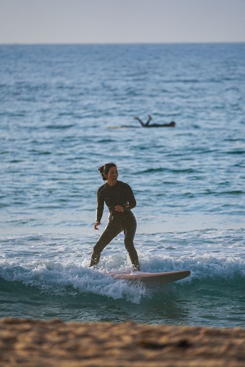 Free Female surfer rides waves at sunset. Perfect for adventure and lifestyle themes. Stock Photo