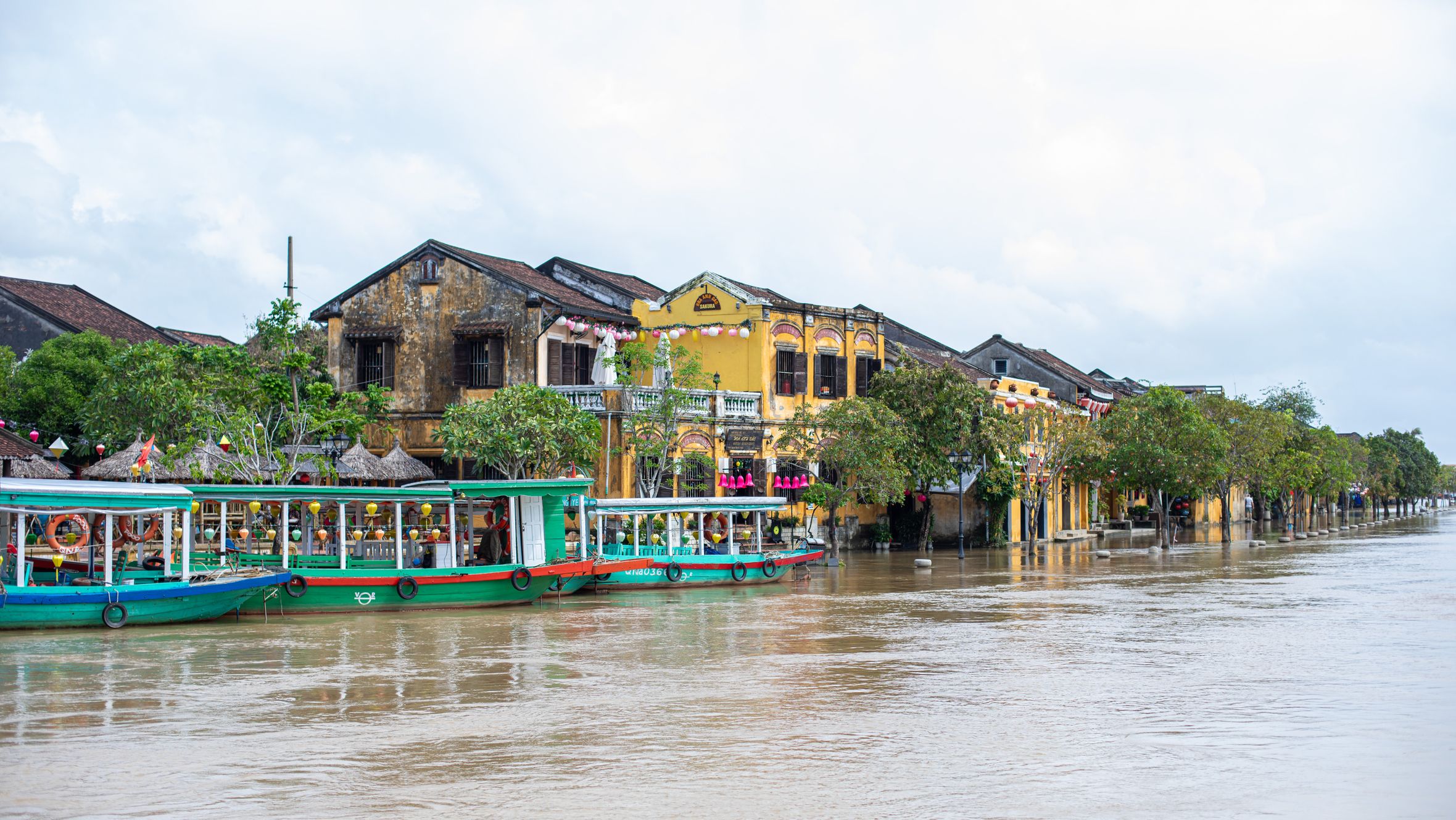 Serene riverside view of Hội An's charming historical architecture and colorful boats.