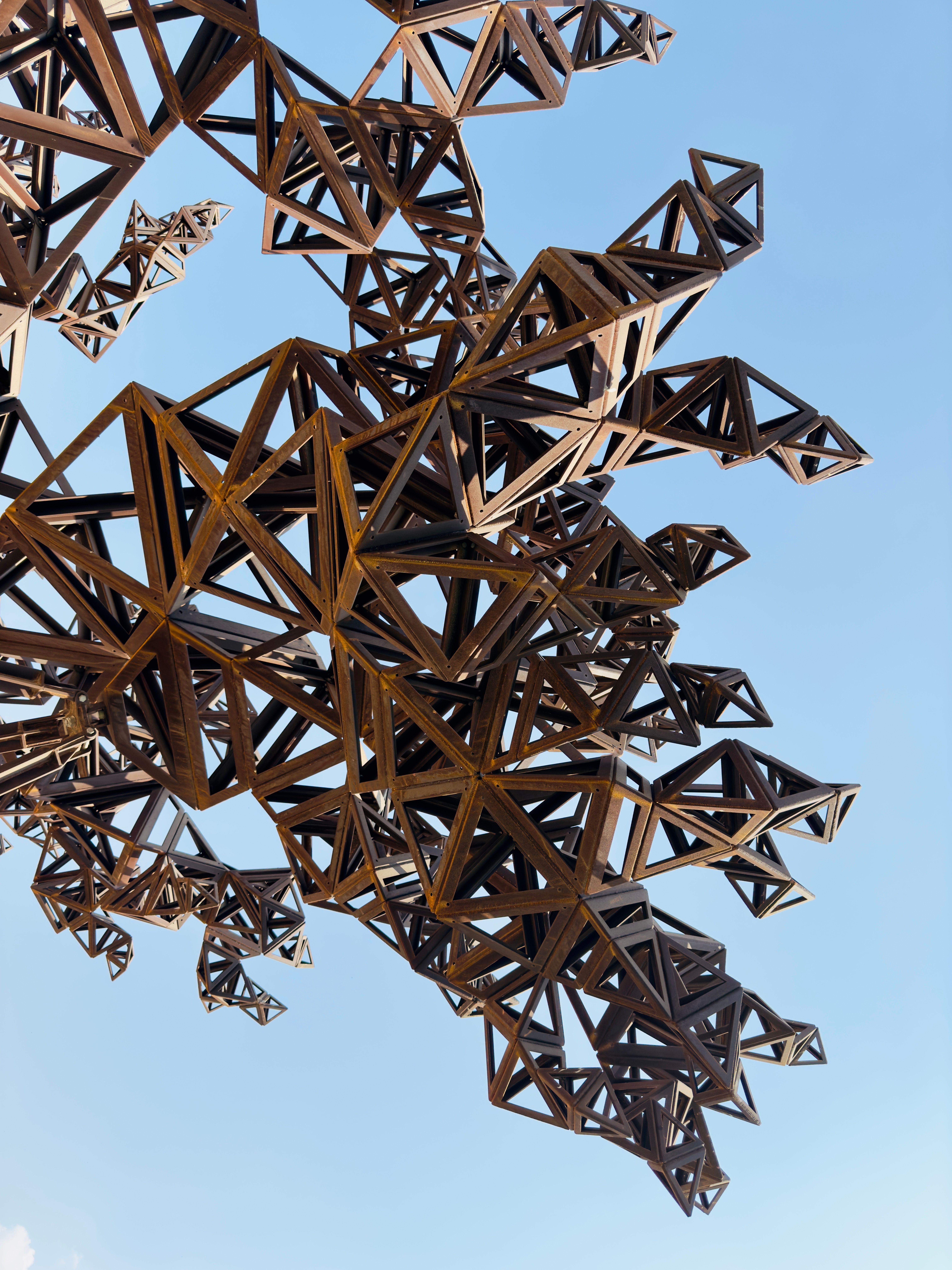 Intricate metal sculpture with geometric design set against a clear blue sky.