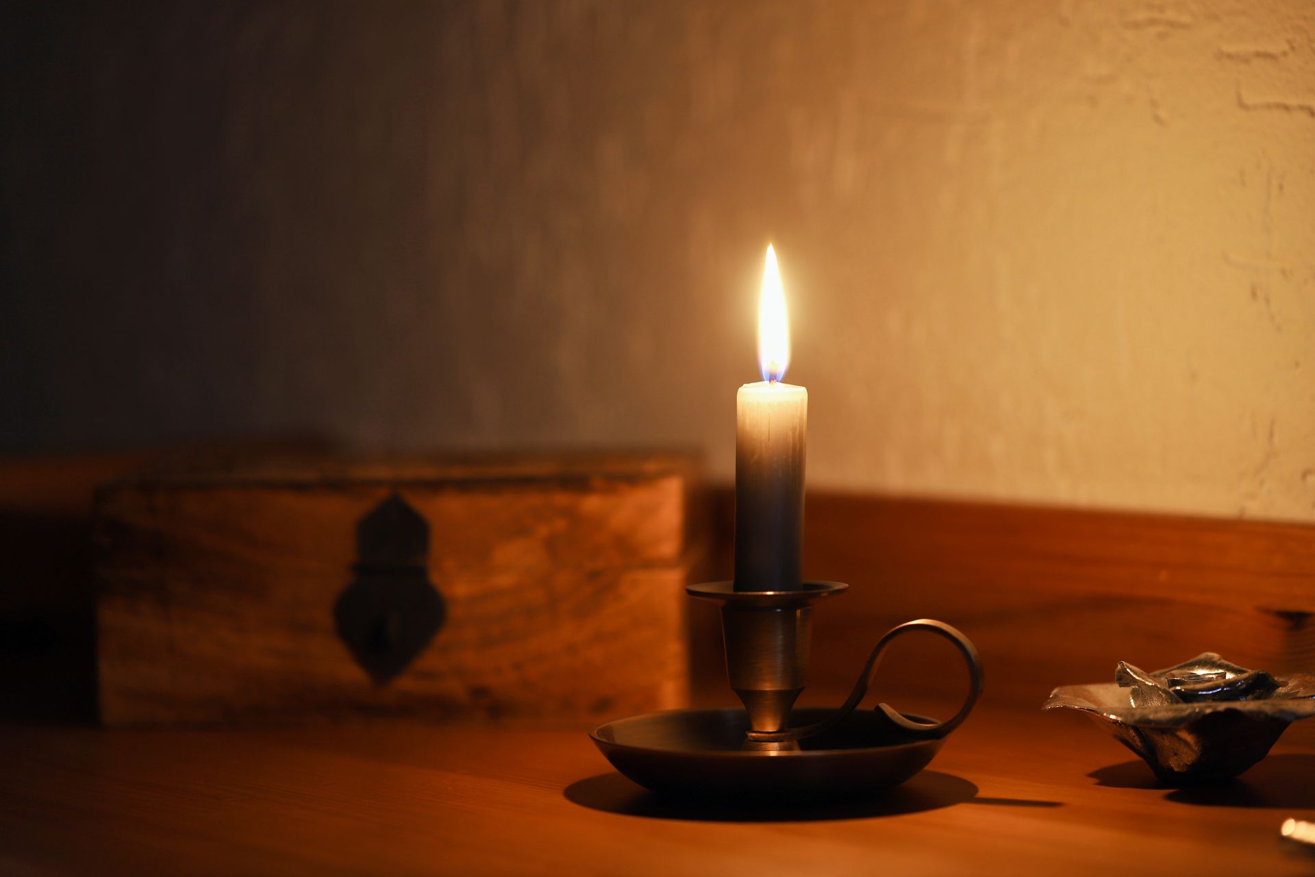 A serene candlelit setting with an antique wooden box and metal candle holder.