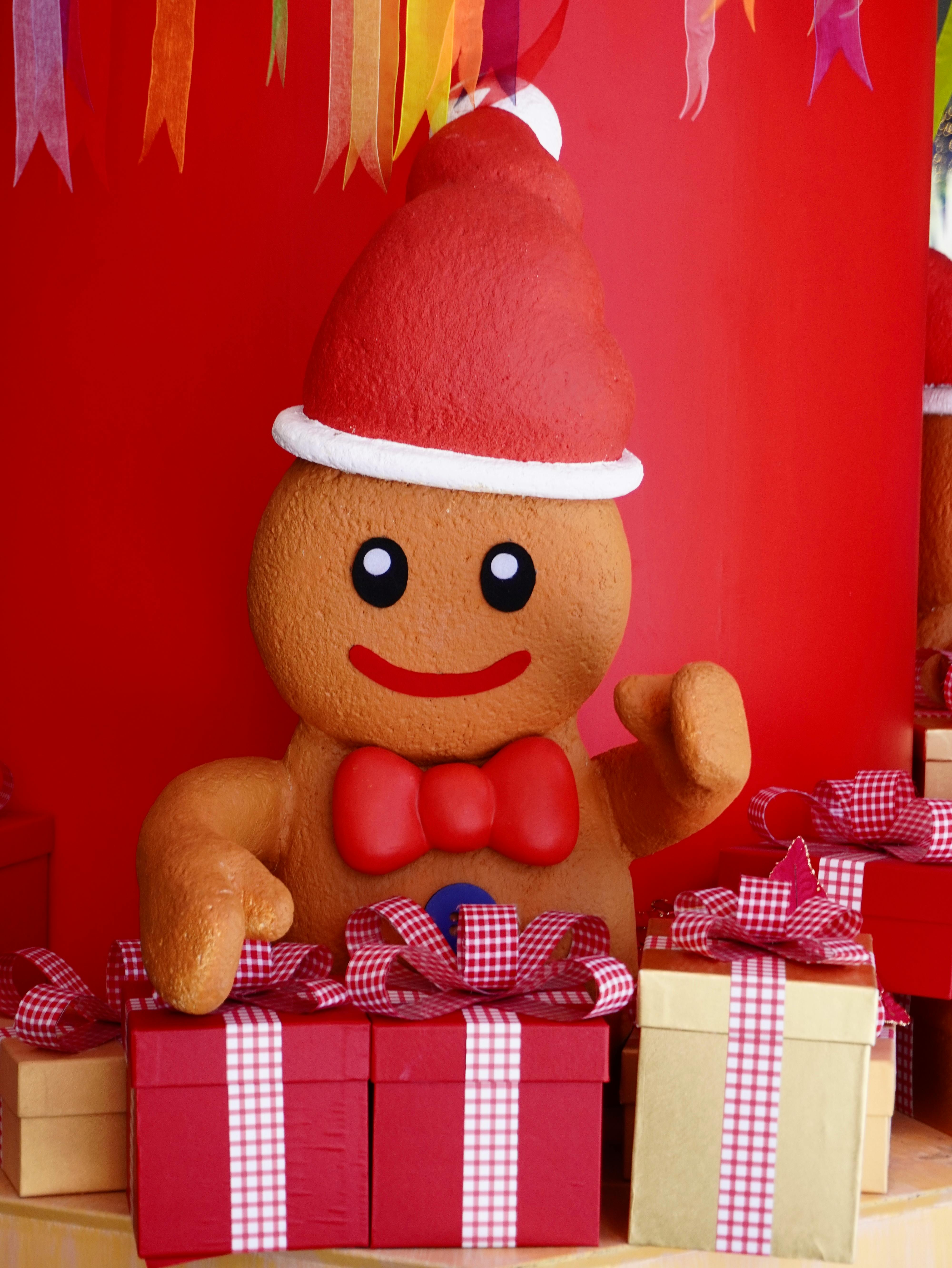 Colorful gingerbread man figure with holiday gifts and decorations.