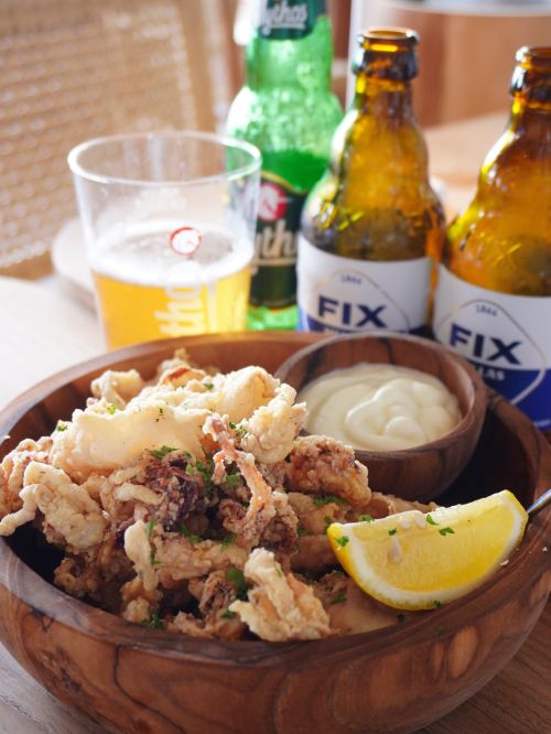 Free Delicious fried calamari served with lemon and beer in a cozy dining setting. Stock Photo