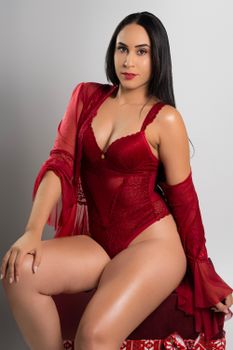 Portrait of a woman in red lingerie with a sheer shawl sitting confidently