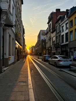 Sunset paints Antwerp street in golden hues, highlighting its historical buildings.
