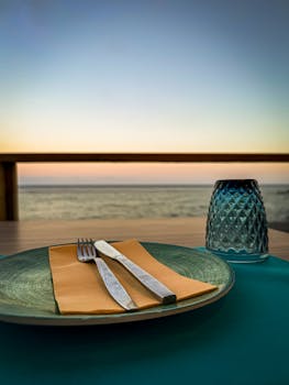 Elegant table setting by the sea at sunset, perfect for seaside dining.