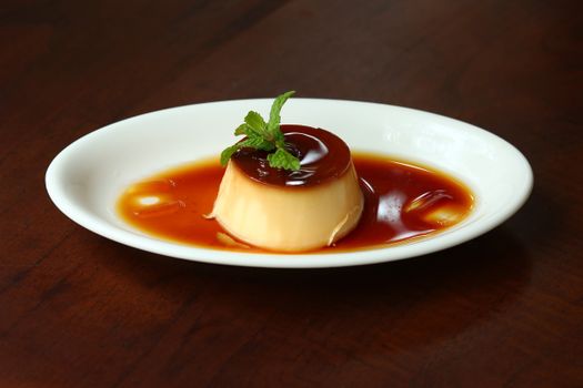 Vietnamese flan dessert in caramel sauce on white plate, vibrant presentation.