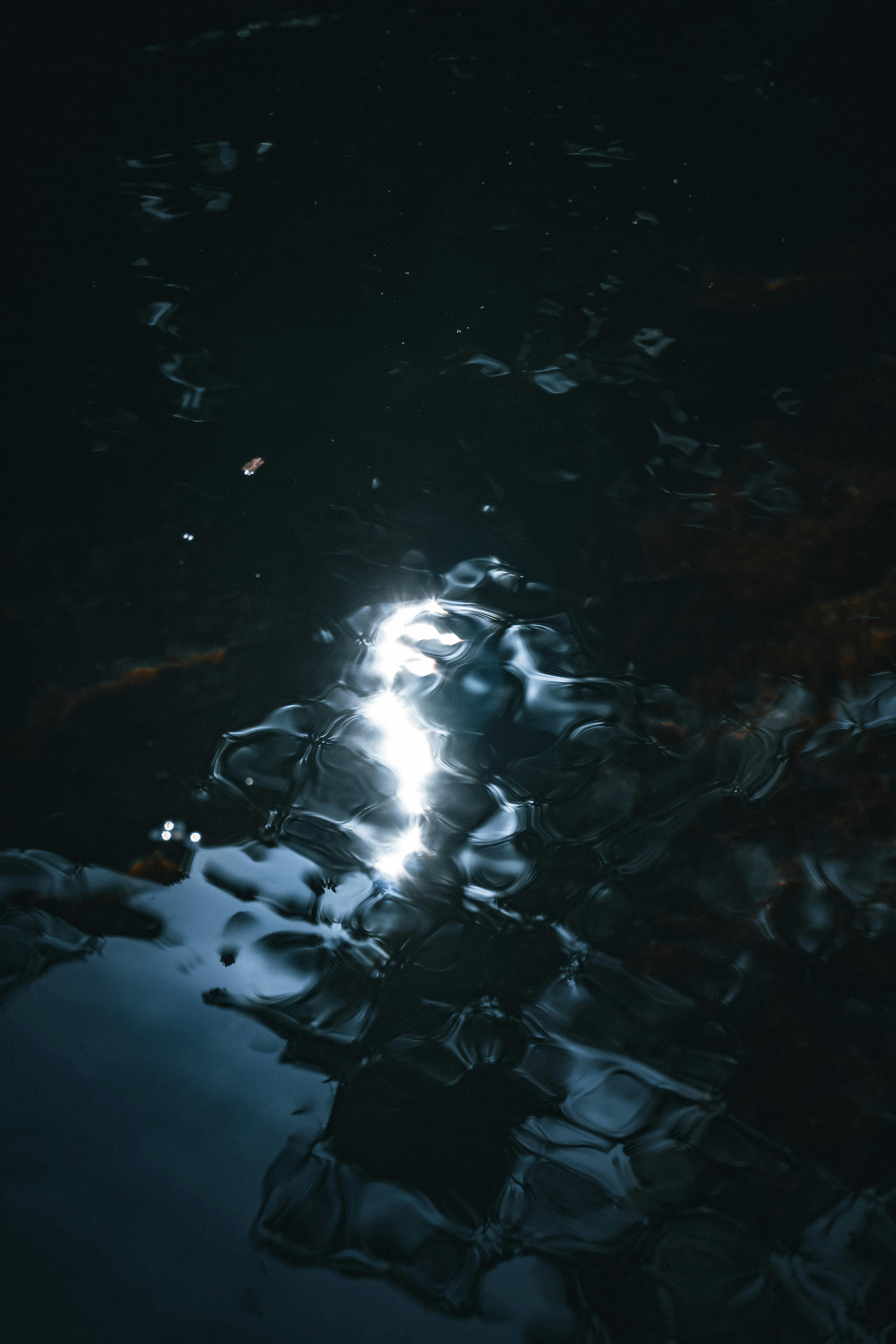 gratis Abstract beeld van licht dat weerkaatst op donker water, waardoor unieke patronen ontstaan. Stockfoto