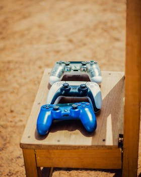 Three gaming controllers placed on a wooden chair in outdoor setting.