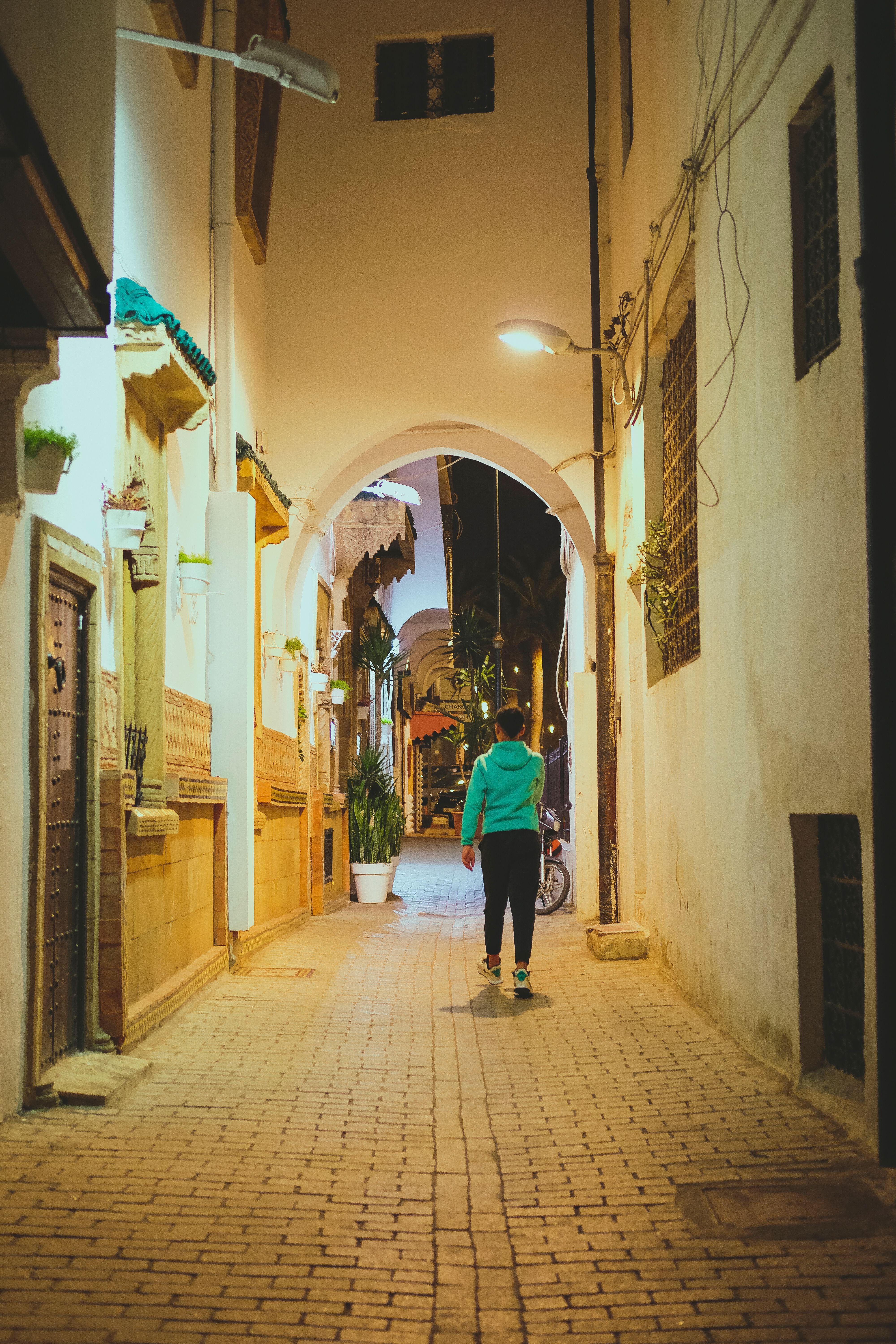 A person walks through a dimly lit historic alleyway in Rabat at night.