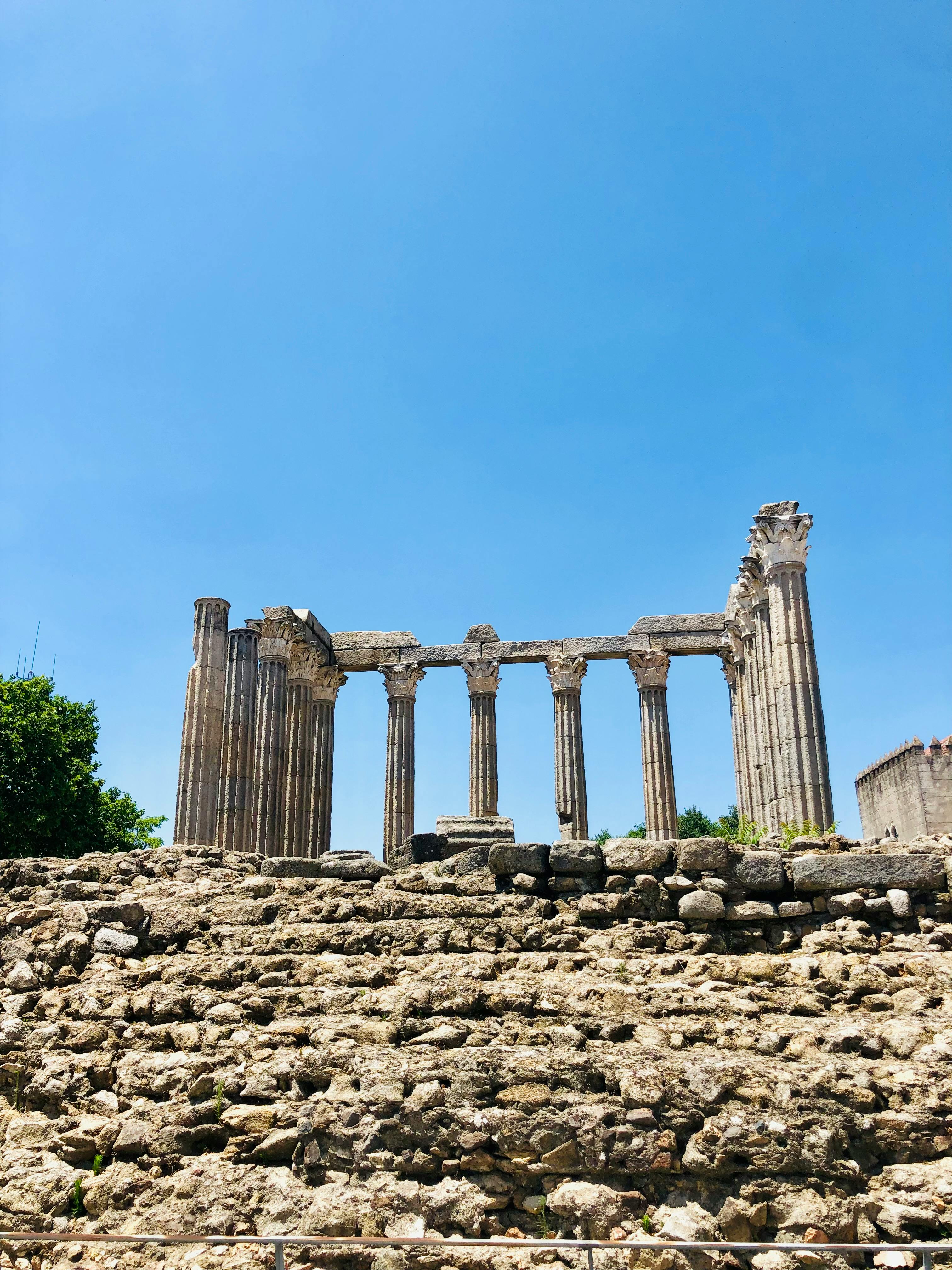 Explore ancient Roman ruins with towering columns and a bright blue sky in atmospheric Alentejo, Portugal.