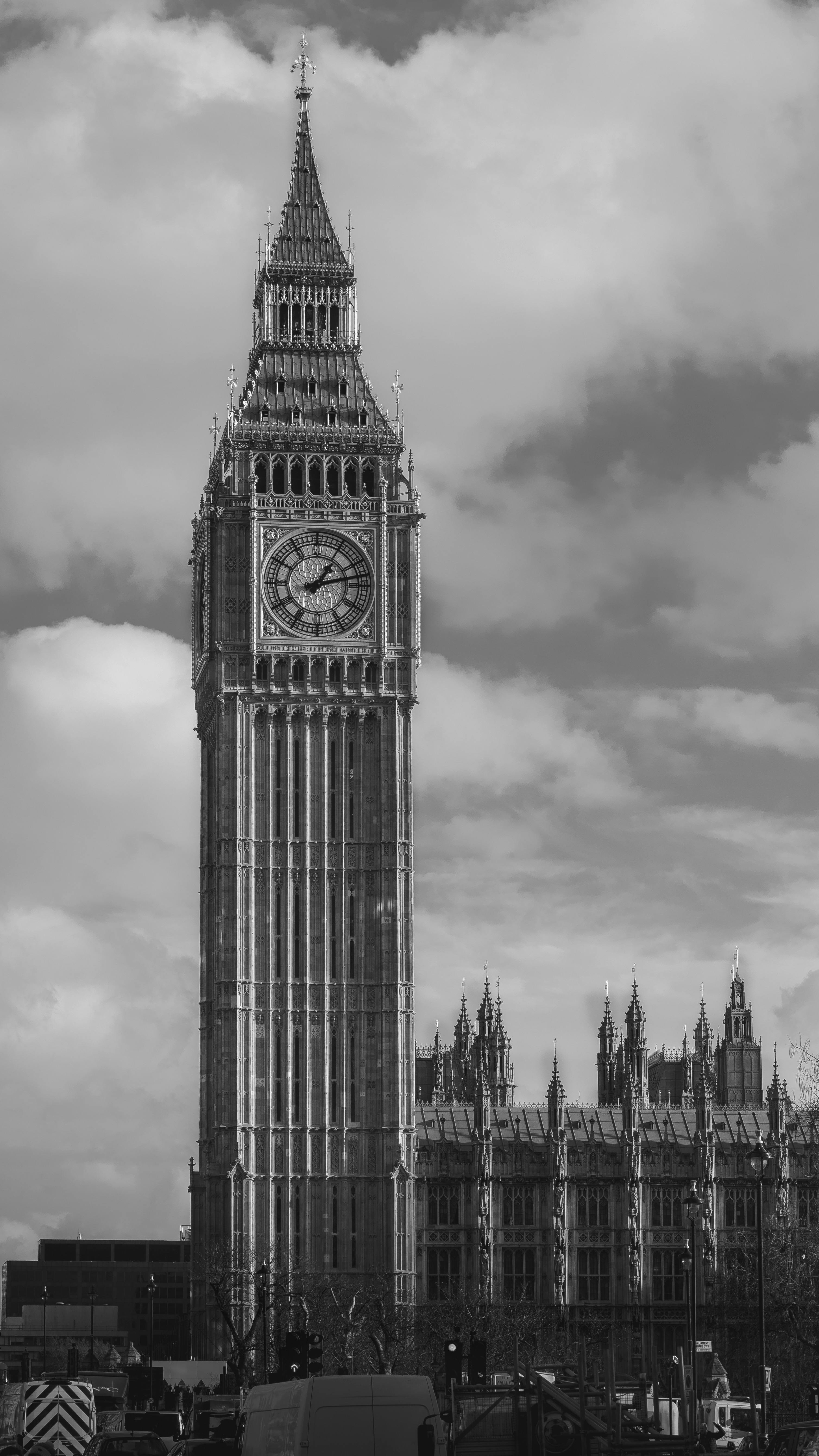 Black and white image of Big Ben and the Houses of Parliament in London against cloudy sky.
