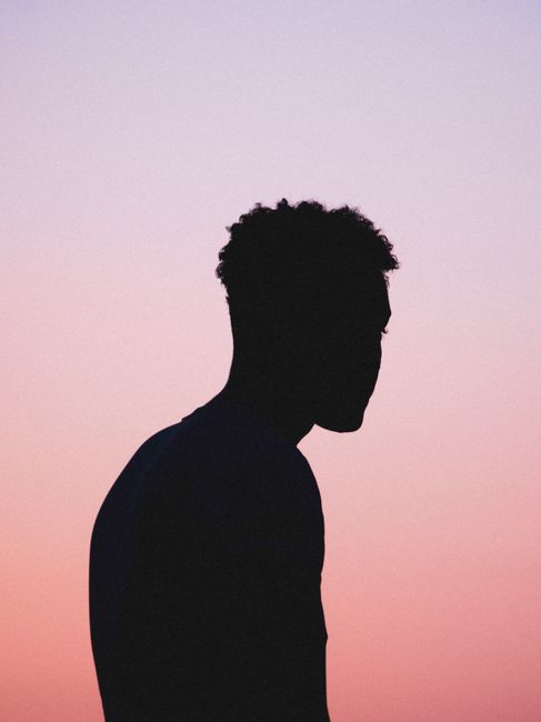 Silhouette of a young man against a vibrant pink sky in Alexandria, Egypt during sunset.