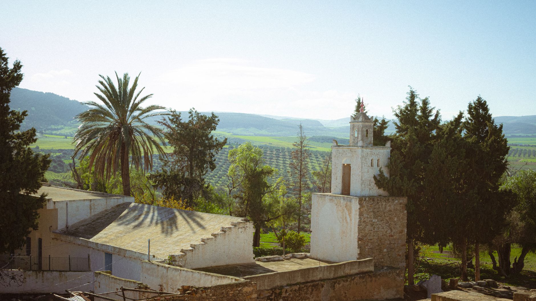 A historic structure surrounded by palm trees and fields in Ben Arous, Tunisia.