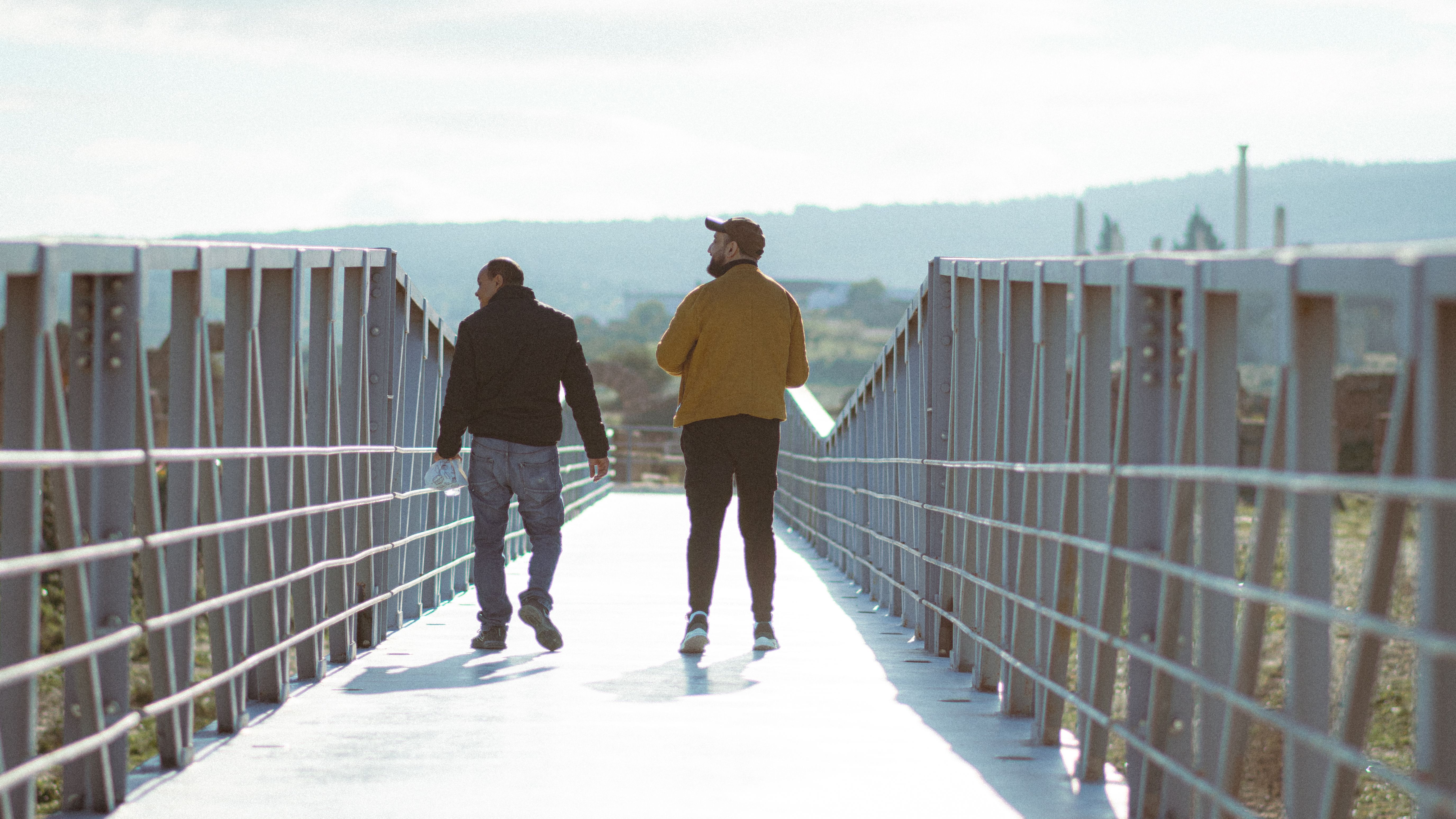 Two men walk across a steel pedestrian bridge, capturing a moment of urban exploration.