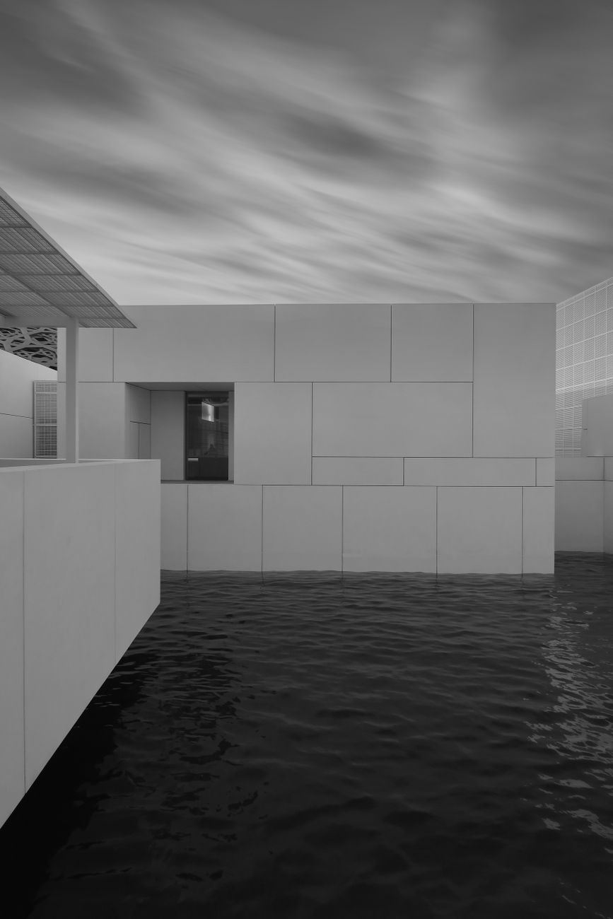 Black and white photo of a modern building with geometric design over water.
