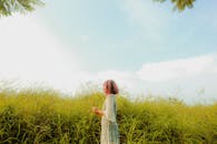 夏日天空下，一个女人在郁郁葱葱的草地上享受着宁静的时刻