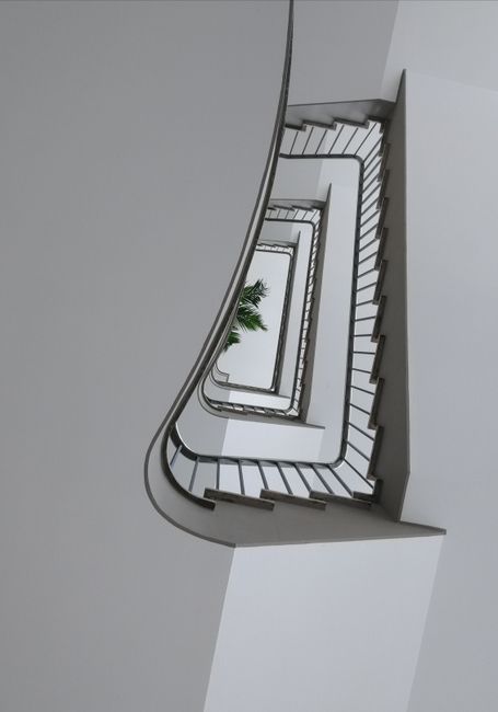 Aerial view of an elegant, modern spiral staircase with sleek railings in a contemporary building interior.