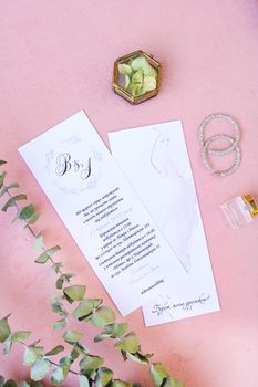 Chic wedding invitations with decor on soft pink surface, perfect for romantic occasions.