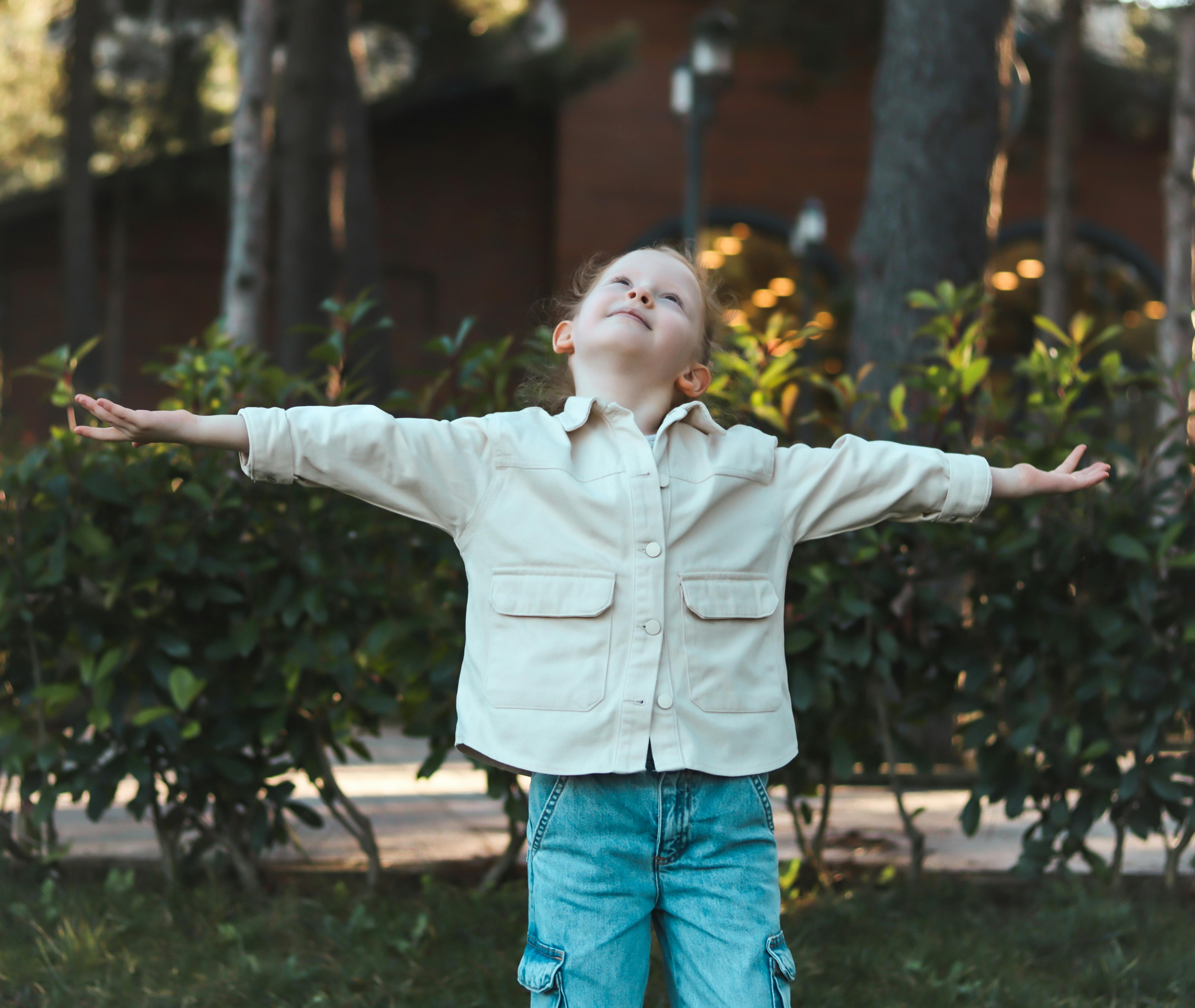 bezplatná Dítě objímající přírodu s otevřenou náručí v klidném venkovním prostředí. Základová fotografie