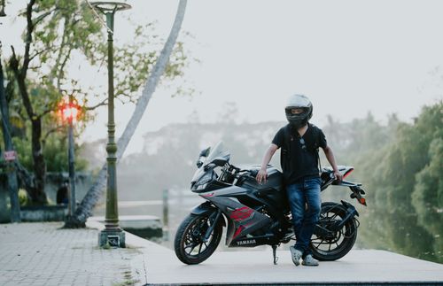 Free A person standing with a motorcycle near a river at dawn, exuding adventure and freedom. Stock Photo