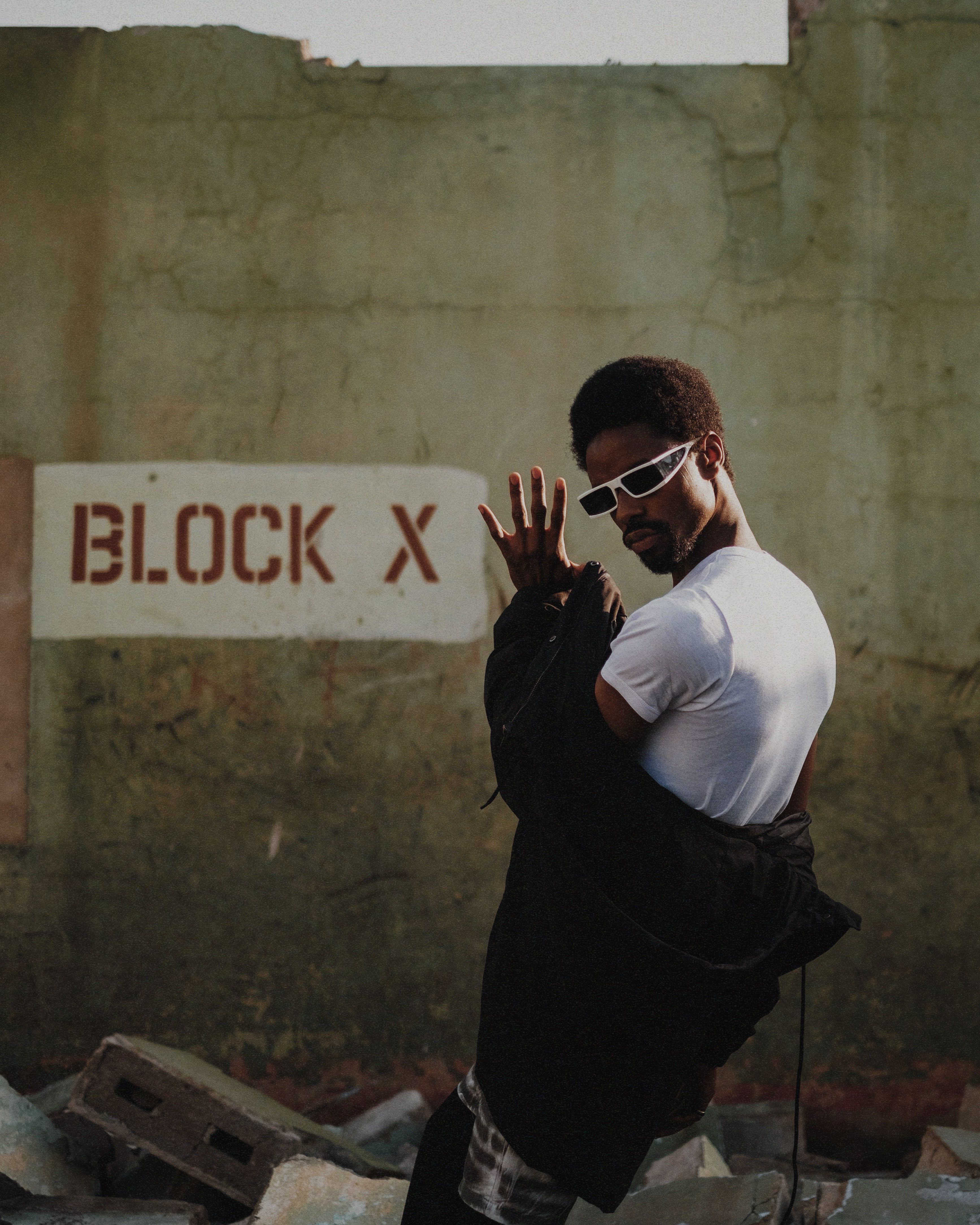 Stylish Man Posing Against Block X Wall in Kaduna · Free Stock Photo