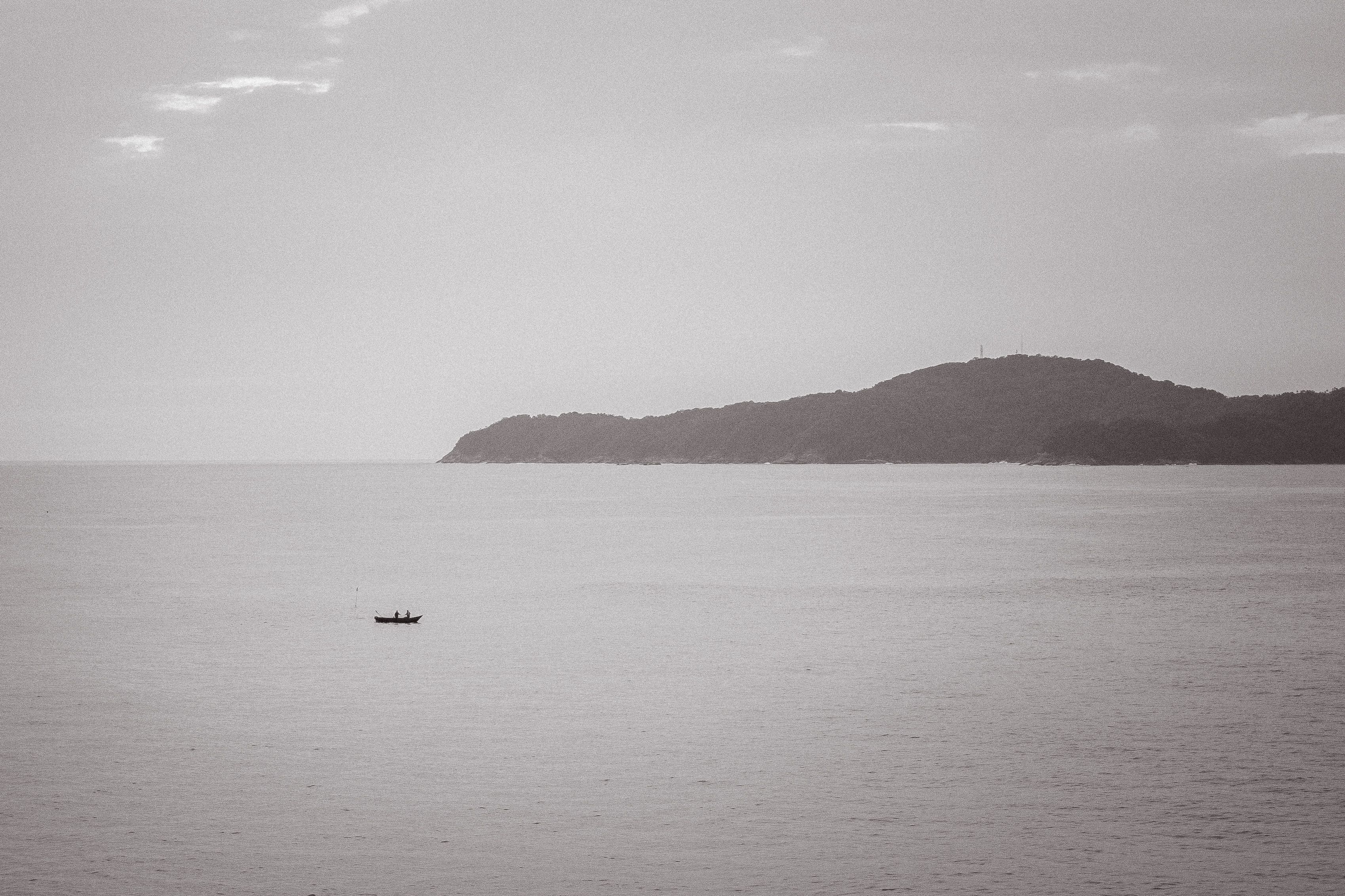 Una costa gris con un barco de pesca bajo cielo nublado