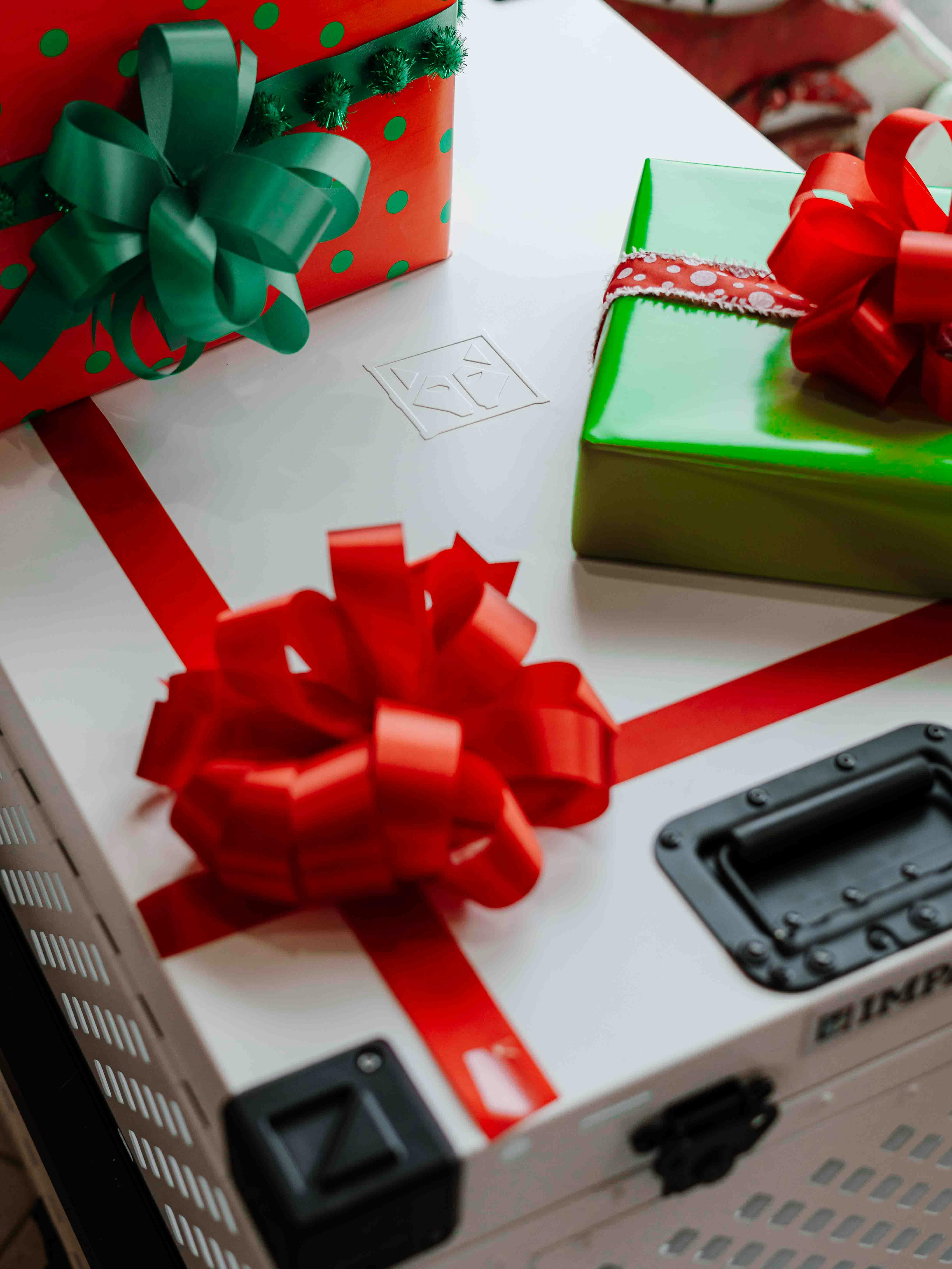 Colorful Christmas presents with red bows on a white dog crate, evoking holiday spirit.