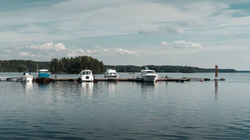Free Tranquil view of boats docked at a Finnish lake marina, surrounded by forest. Stock Photo