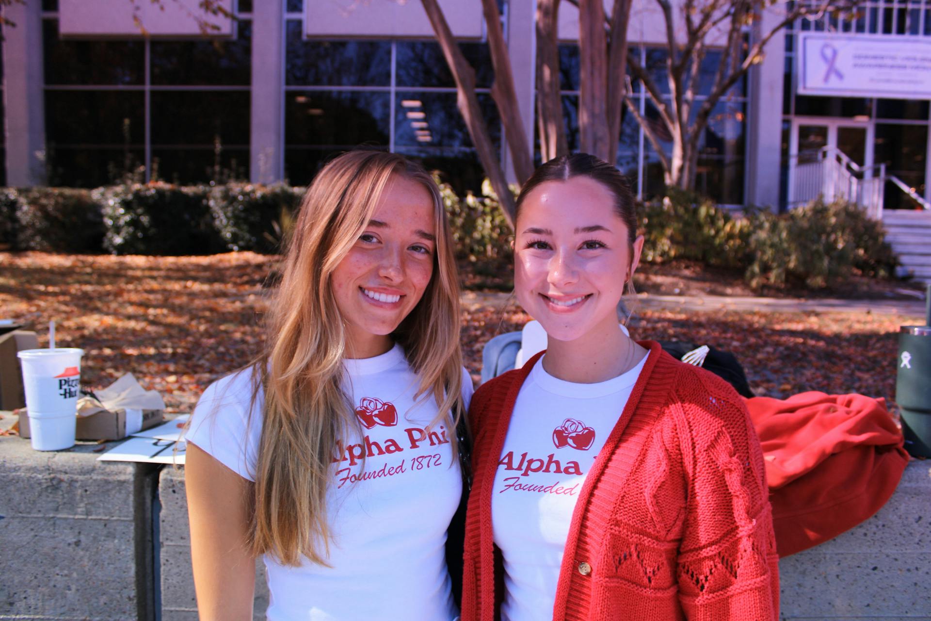 Two young women in Alpha Phi shirts smiling outdoors in Norfolk, Virginia