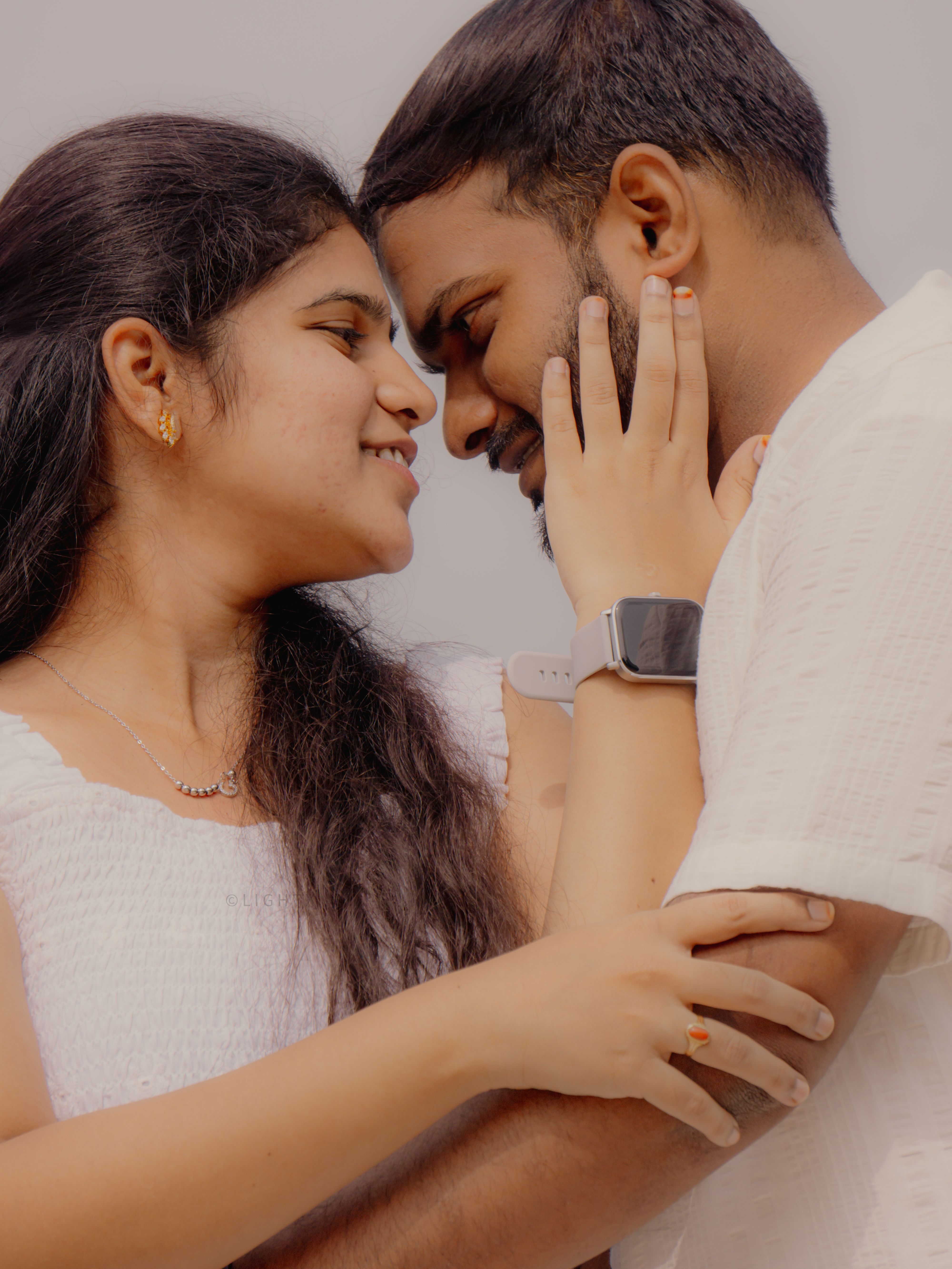 A loving couple sharing a tender moment in a close embrace outdoors.