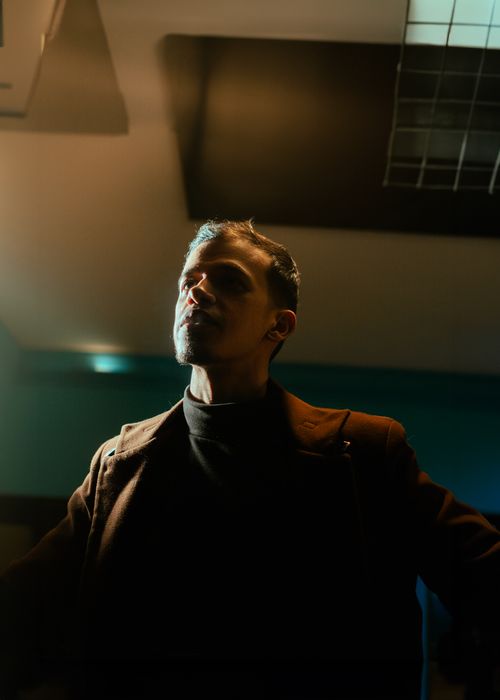 Free A dramatic portrait of a man in a dimly lit indoor setting, creating a mysterious mood. Stock Photo
