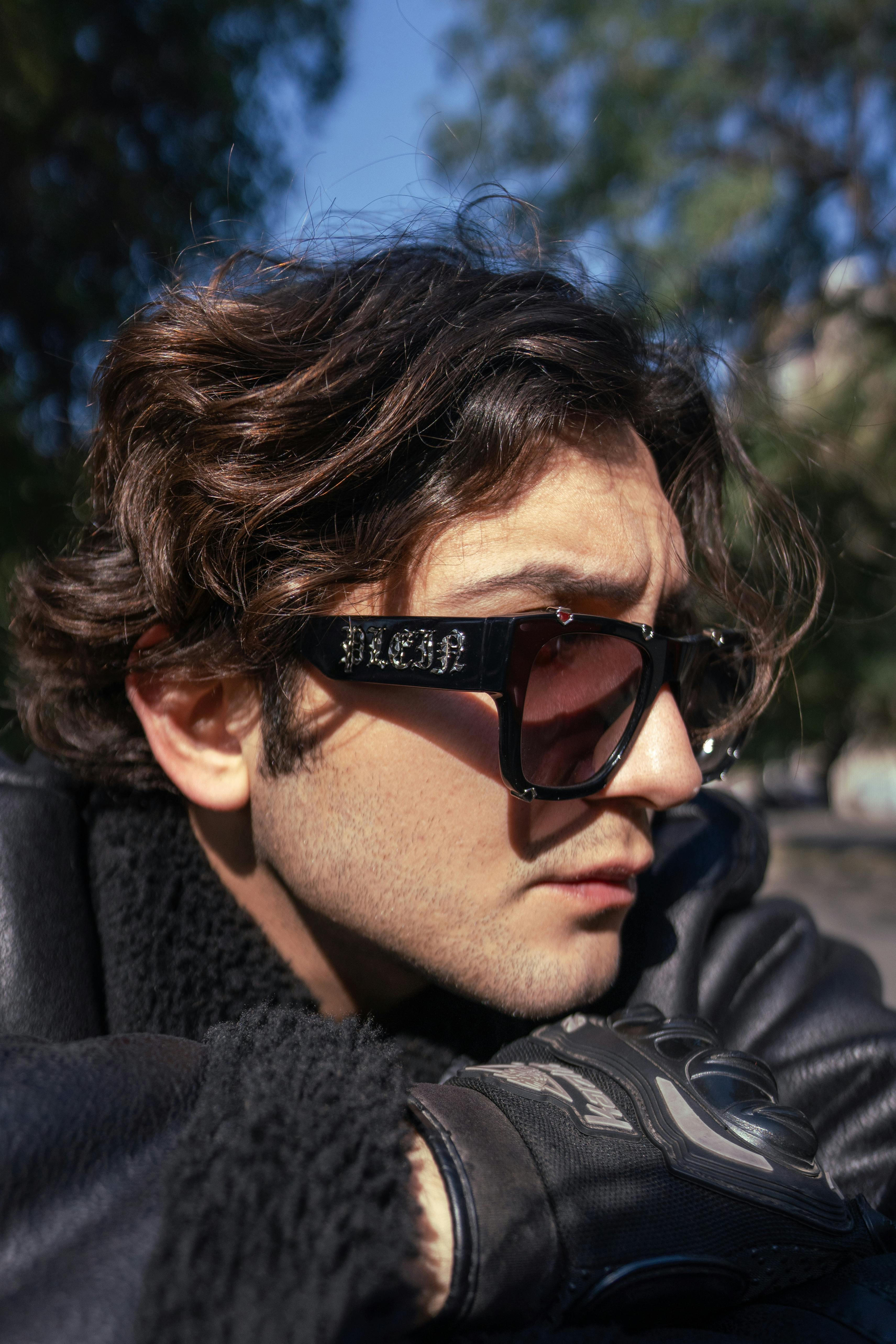 A fashionable man wearing sunglasses outdoors in Baghdad, Iraq. Captures a modern street style vibe.