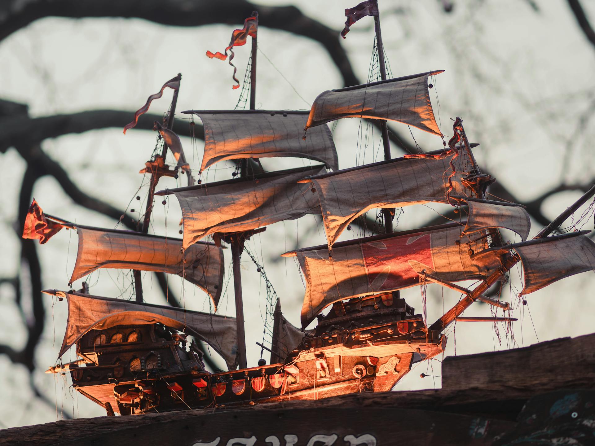 A detailed vintage model ship with billowing sails against a blurred outdoor background.