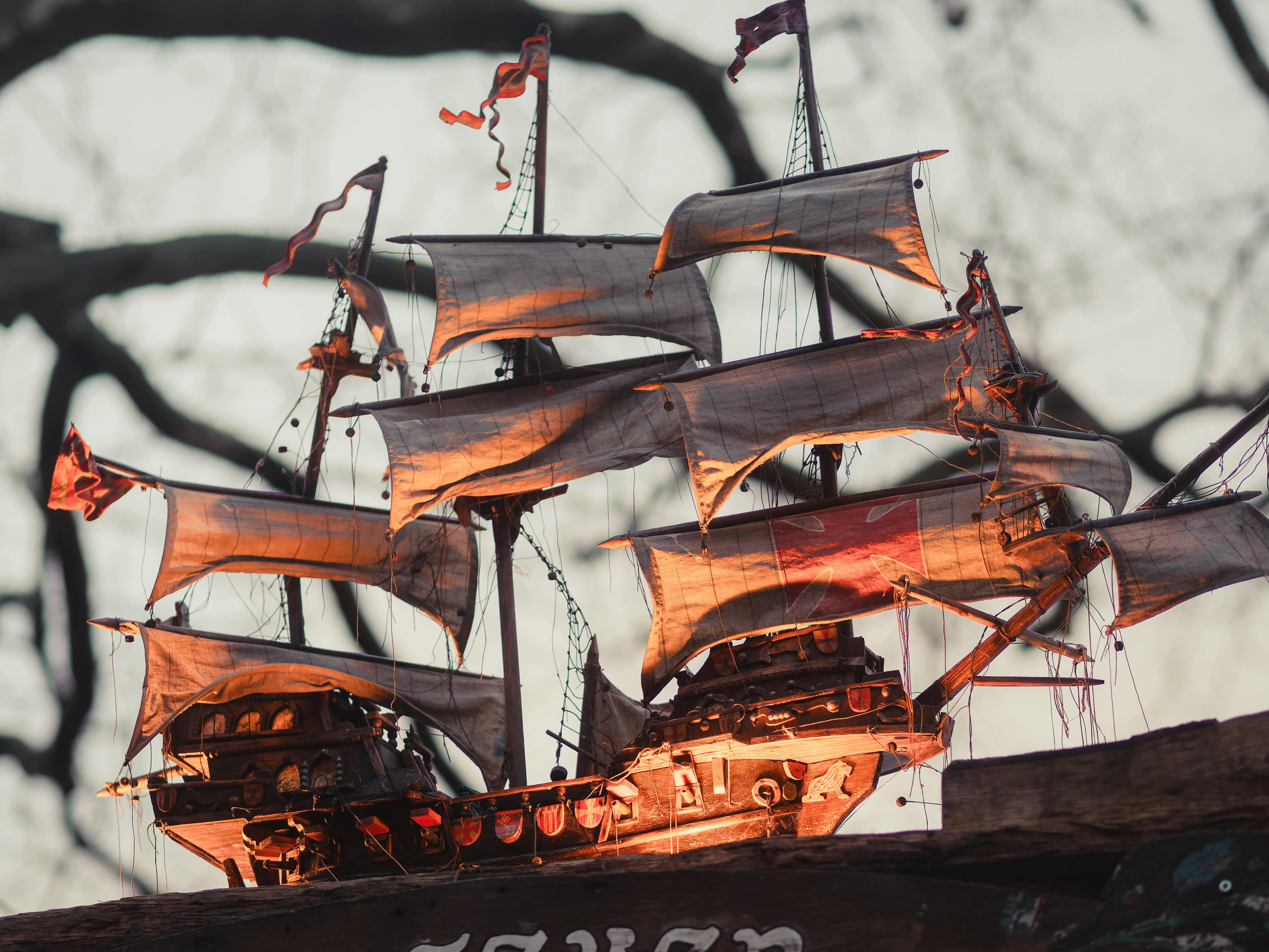 grátis Um modelo de navio vintage detalhado com velas ondulantes contra um fundo externo desfocado. Foto profissional