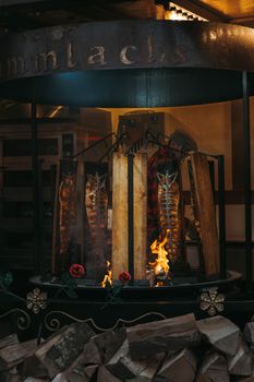 Traditional salmon grilling on wooden planks over an open flame in a rustic market setting.