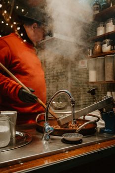 A chef in a red sweater cooks with steam rising in a cozy kitchen setting.