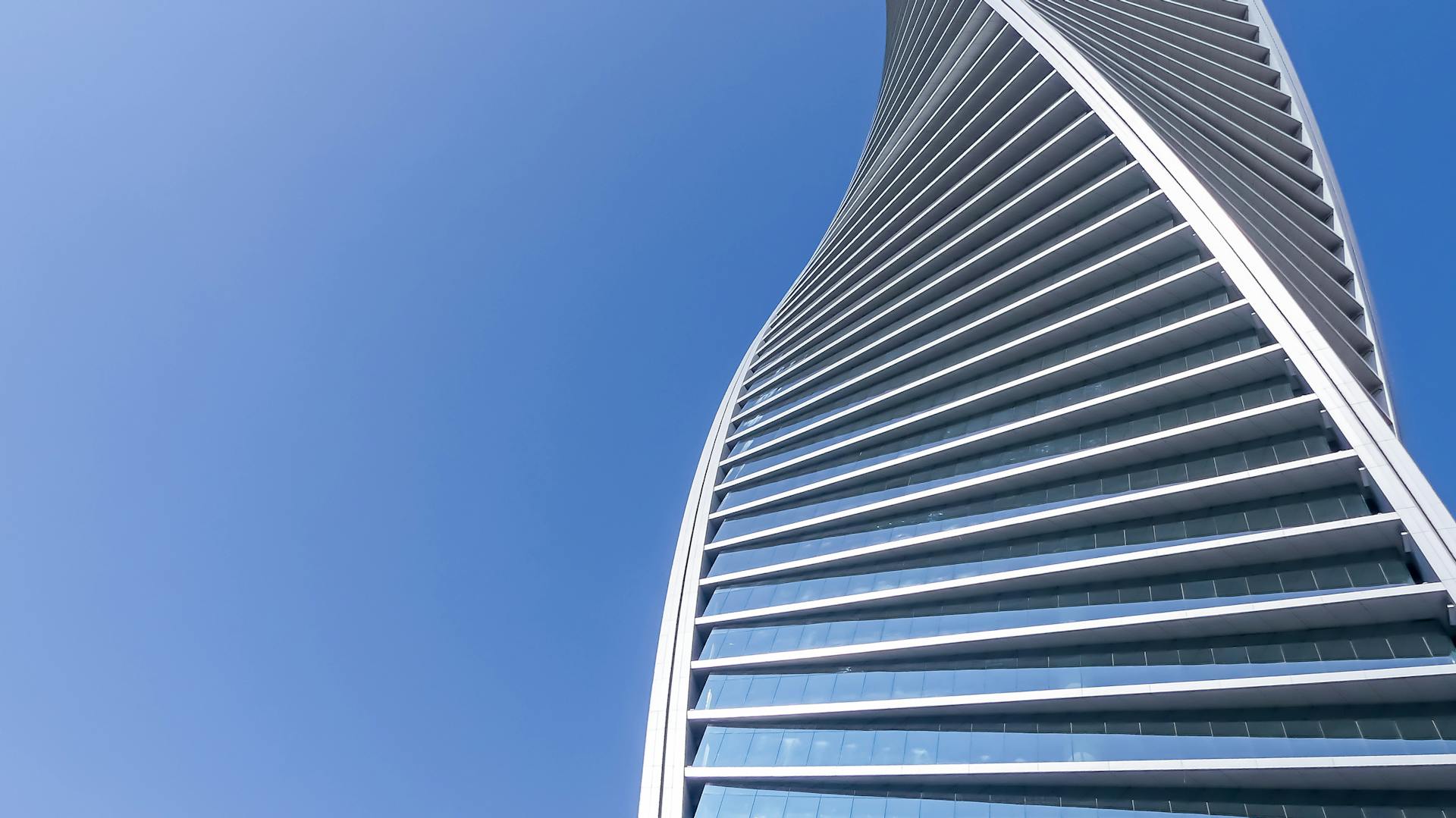 Captivating view of a futuristic skyscraper in Saudi Arabia with a twisting modern design against a clear blue sky.