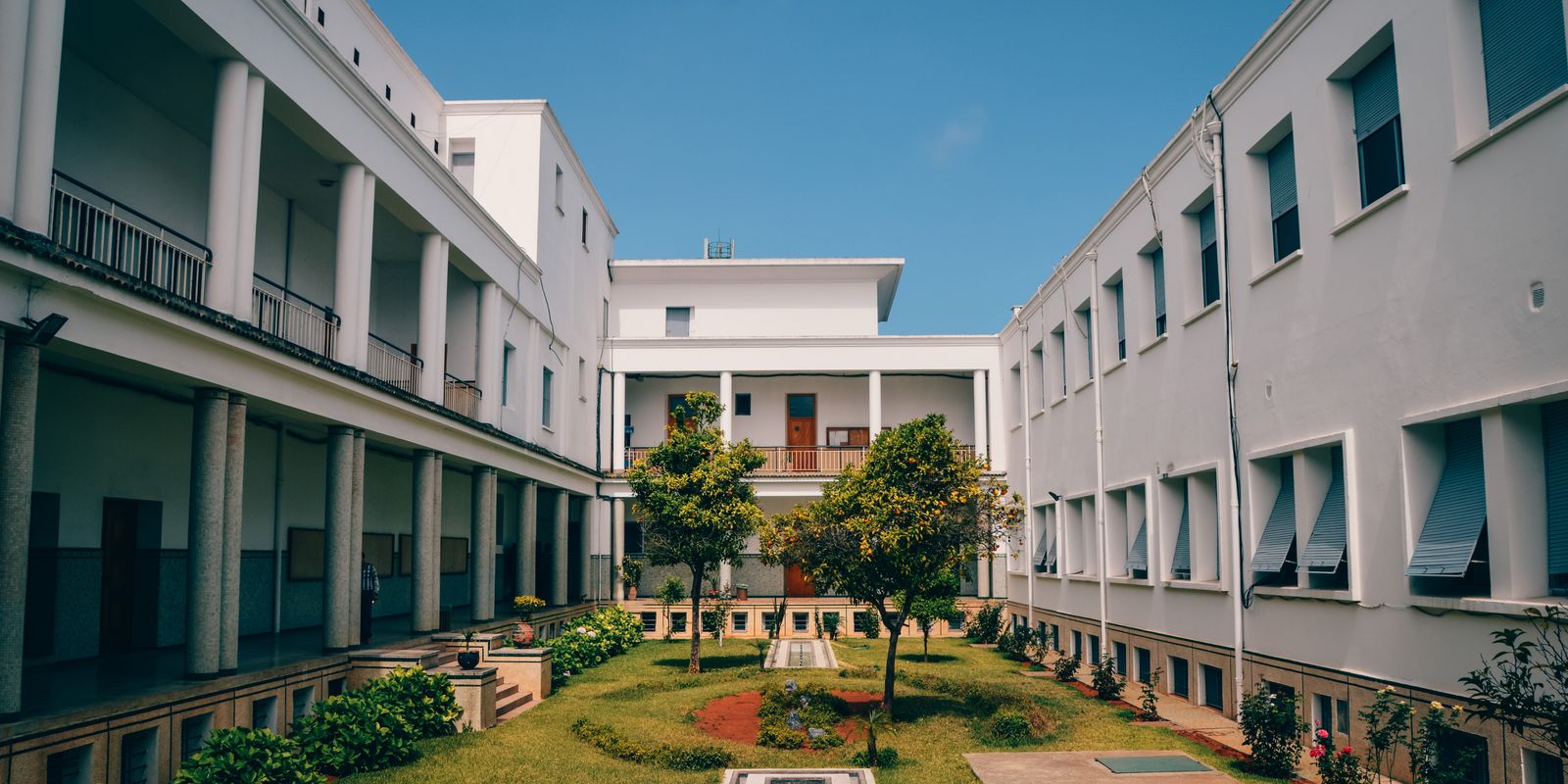 Elegant university building with garden courtyard in Rabat, Morocco under clear blue sky.