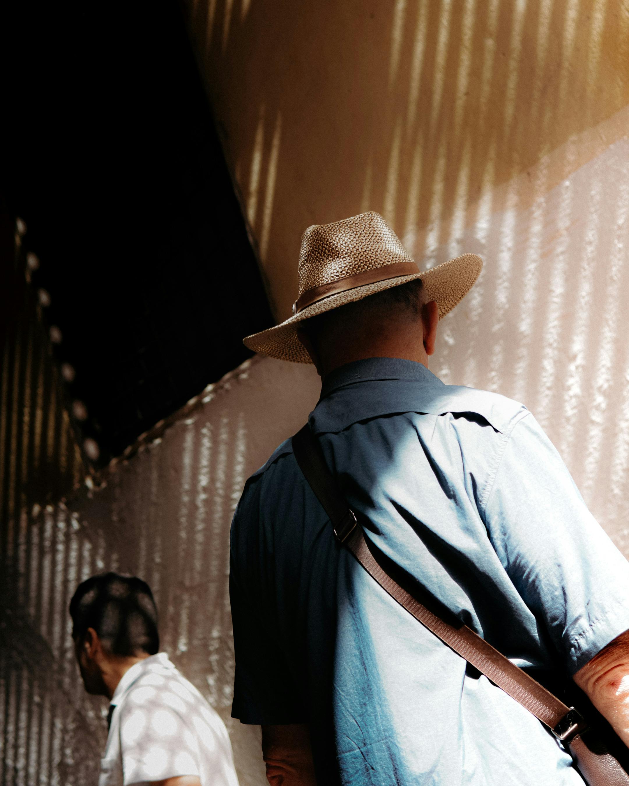 Free Two men in a sunlit passageway, creating a play of light and shadow. Stock Photo
