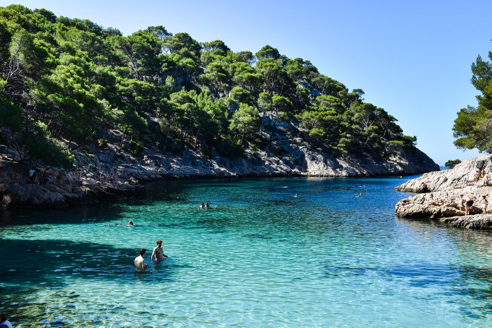 Teluk Mediterania berwarna pirus di Cote d'Azur dengan tebing berhutan pinus