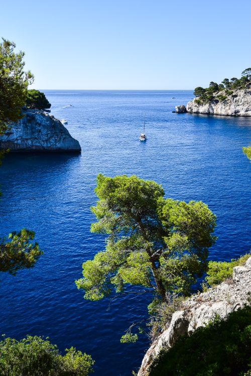 Free A stunning view of calanques in Provence-Alpes-Côte d'Azur, France with a sailboat on a sunny day. Stock Photo