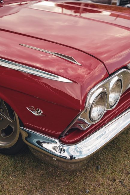Close-up of a vintage red muscle car showcasing chrome details and classic design.