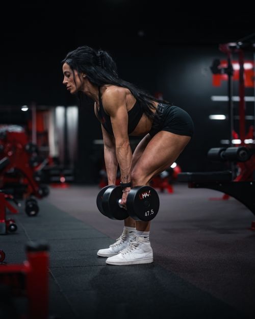 Free Strong female athlete lifting dumbbells in a gym setting, focused on strength training. Stock Photo