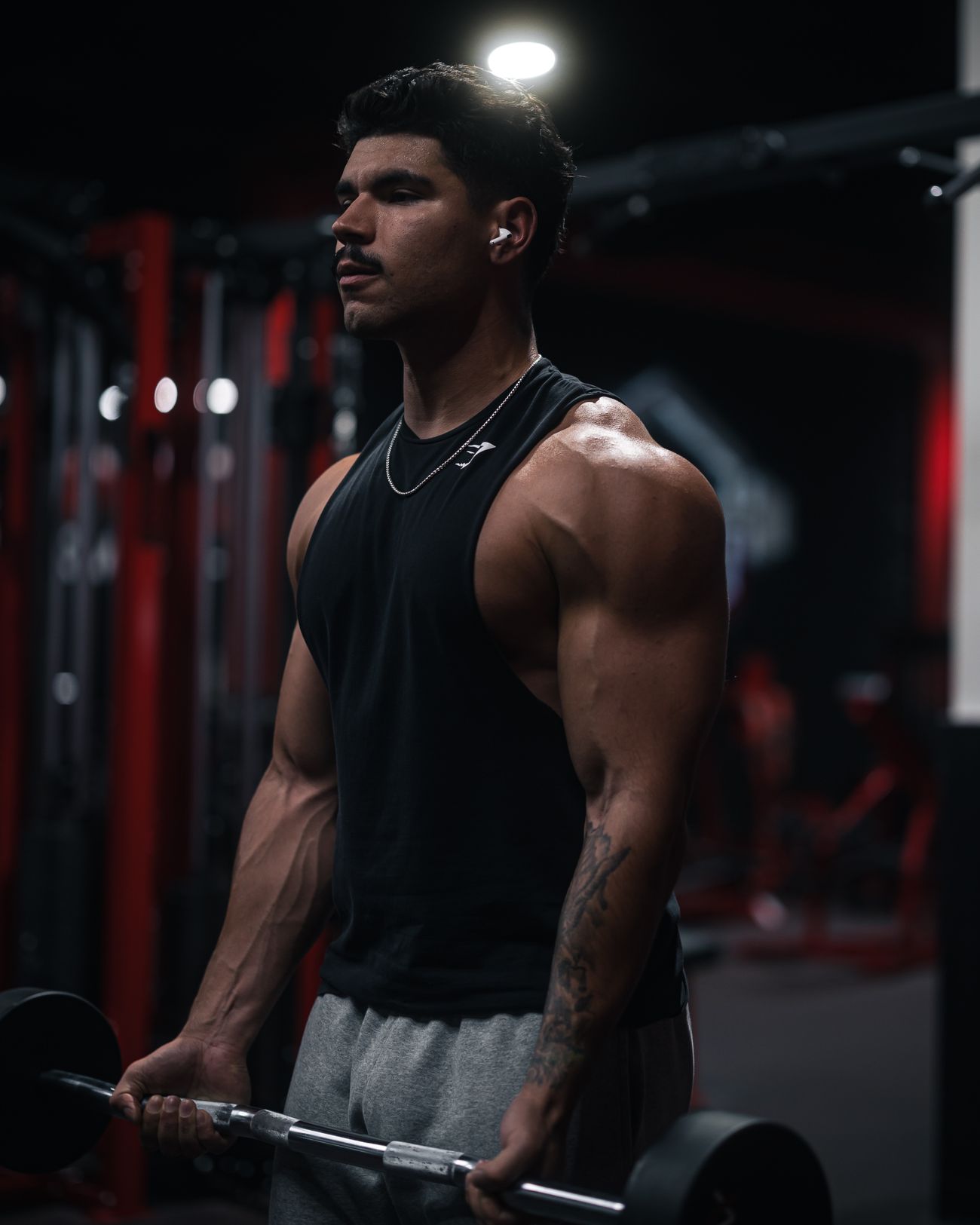Hombre levantando hierros en gimnasio oscuro