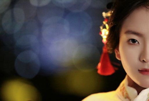 Half portrait of a woman in traditional Asian clothing with soft focus bokeh lights.