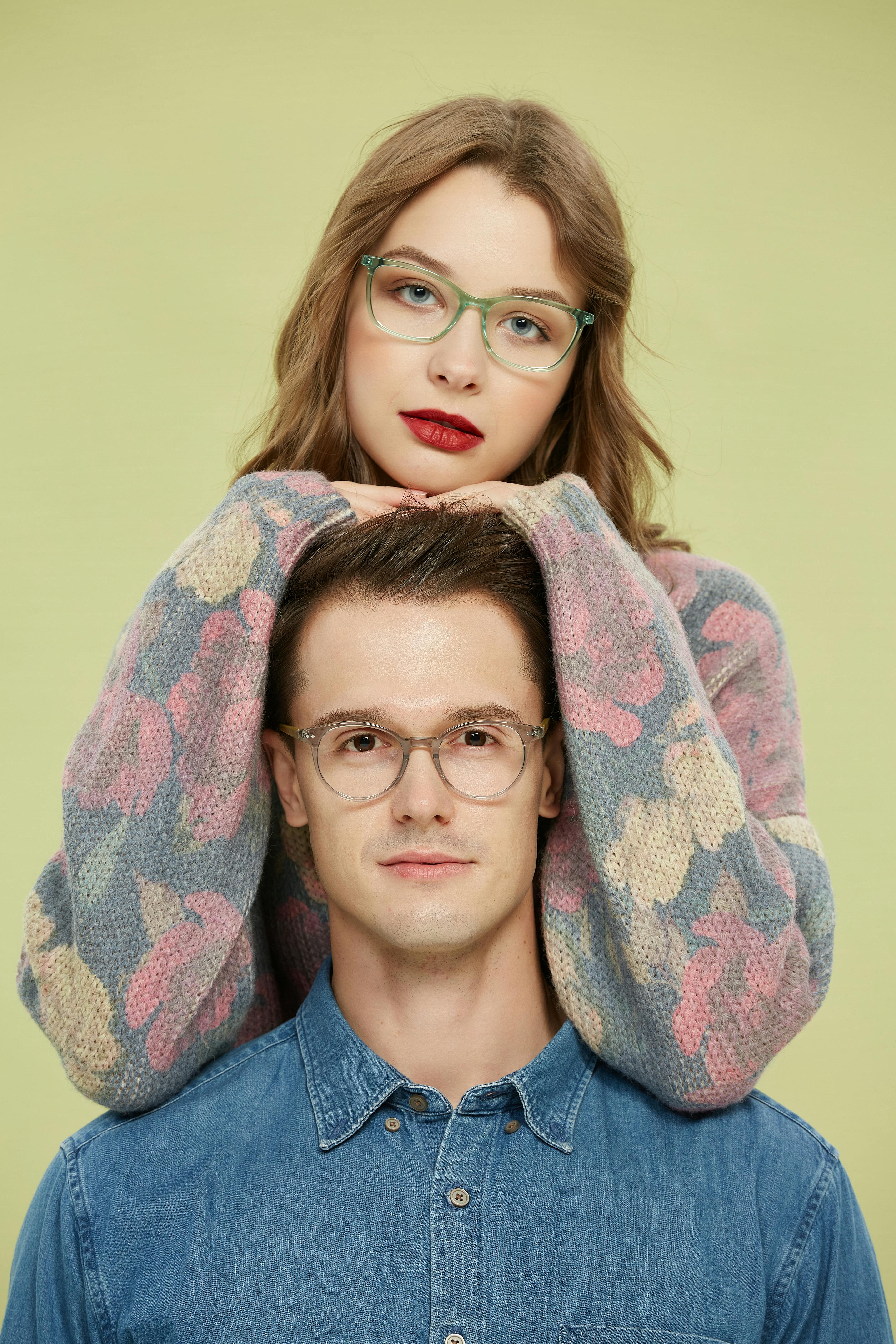 A fashionable couple wearing eyeglasses in a vibrant portrait setting.