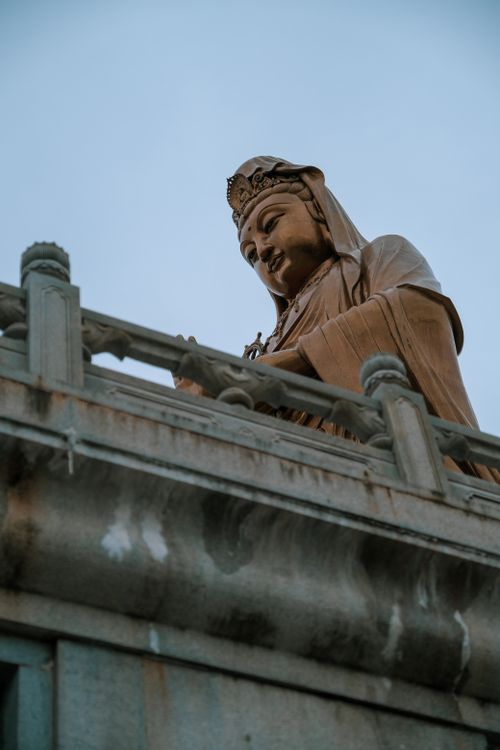 Free Low angle view of the Guanyin statue with serene expression and traditional architecture. Stock Photo